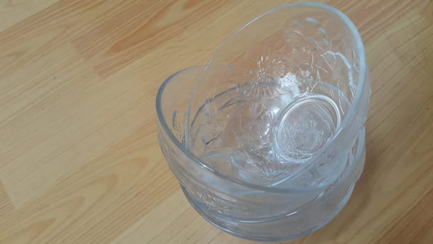 Top view of empty white glass bowls on a wooden floor. Glass bowl with flowers made on its wall