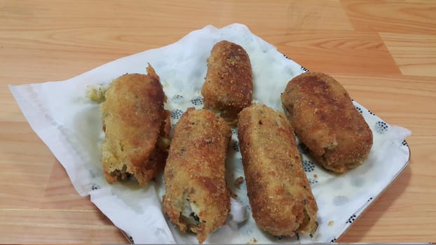 Closeup perspective view of home made spicy and delicious croquettes served in ceramic plate over wooden floor