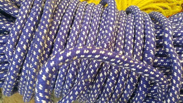 Closeup of bright color braided plastic ropes. Hanks or coil of bright colored plastic rope interwoven which are used for climbing and tightening materials.