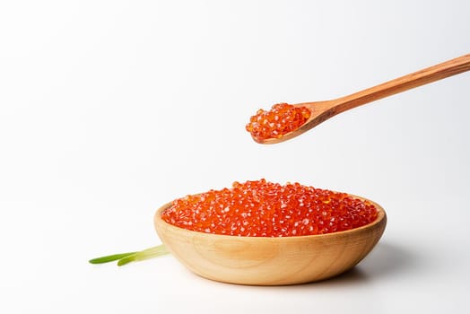 Red caviar in a wooden cup on a white background with a spoon. Place for advertisement, logo, label, mockup, mock-up.