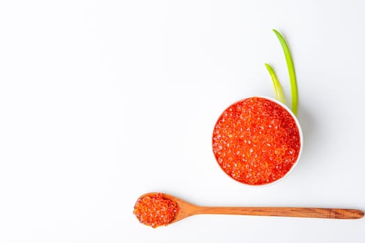 Red caviar in a wooden cup on a white background with a spoon. Place for advertisement, logo, label, mockup, mock-up.