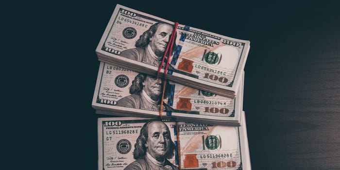 Wads of dollars in cash on a dark table. Three hundred-dollar packs.