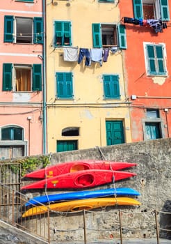 Kayaks strapped to retention wall and house facades at the village of Riomaggiore in Italy