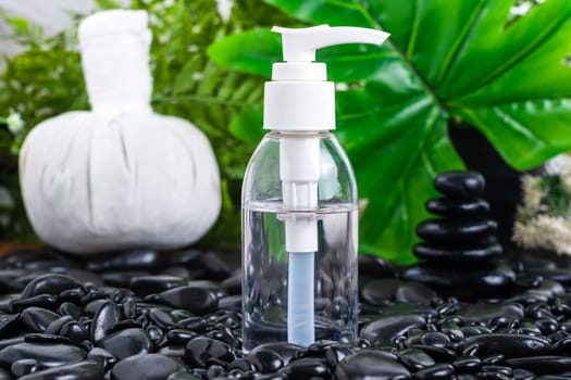 Thai Spa massage setting with serum oil bottle  mock up or essential oil on black stone against green leave background