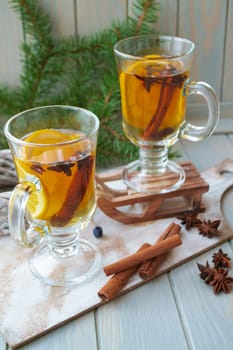 Hot tea in glass with spices on a wooden background. Still life, seasonal and holidays concept. Vertical image