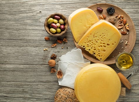 Assortment of cheese, nuts and wine on wooden table. Top view. Free space for text.