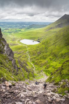 Group of hikers climbing Devils Ladder, one of most difficult trails, to reach highest Irish mountain Carrauntoohil in Ring of Kerry, Ireland
