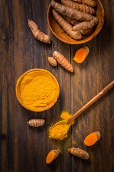 Turmeric root and powder (Curcuma longa) as cooking ingredient on wooden background