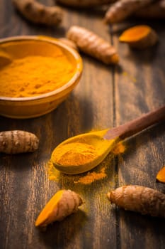 Turmeric root and powder (Curcuma longa) as cooking ingredient on wooden background