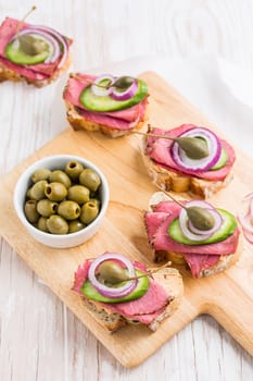 Open roast beef sandwiches with vegetables, olives and capers