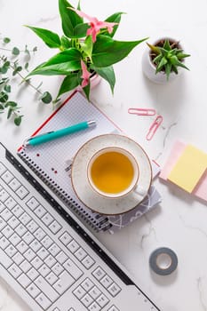 Flat lay home business desk with communication device with cup of tea and writing tools. Feminine business mockup, copyspace, white background.