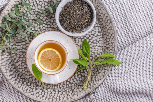 Healthy detox ginger and sage tea with lemon on tray
