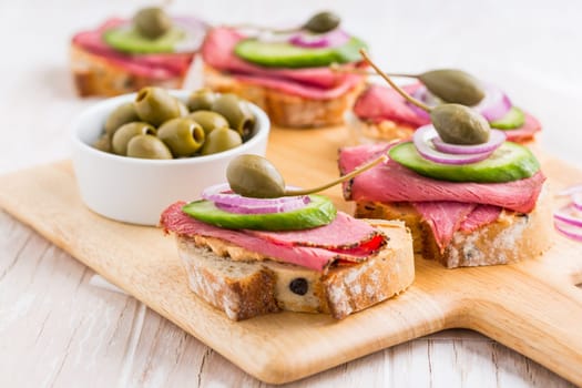 Open roast beef sandwiches with vegetables, olives and capers
