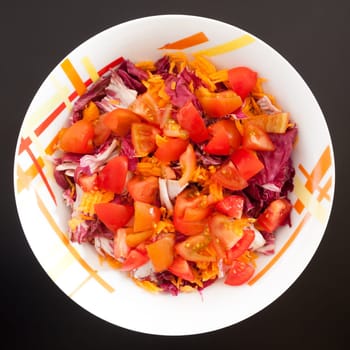 Salad with carrots and tomatoes on black table, top view. Food background