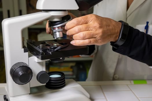 Biology lesson. Teacher is using an optical microscope to carry out her lesson.