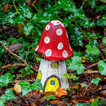 Artificial childhood display of a fly agaric red and white wooden house mushroom in an enchanted fairy toadstool woodland during the autumn fall season of November, stock image photo