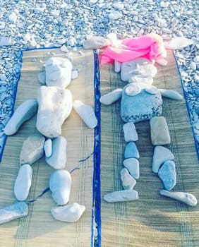 Figures of people on the beach are laid out of stones.