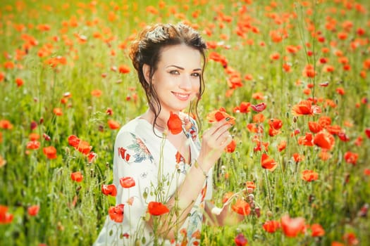 A beautiful girl in a field of blooming red poppies.