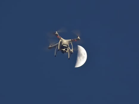 Drone against the moon and blue sky. Flying drone with camera.