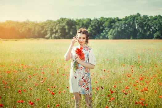 A beautiful girl in a field of blooming red poppies.