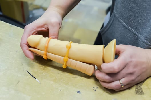 Rubber products factory for a sex shop. Workers process rubber penises. Reduction to the presentation of products. Sex toys.