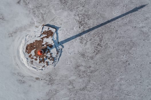 The lighthouse is in winter on the river bank. View from above.