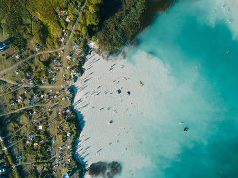 Beach on the shore with white sand and blue water, view from above.