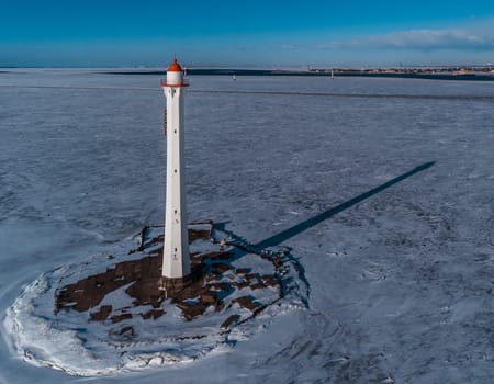 The lighthouse is in winter on the river bank. View from above.