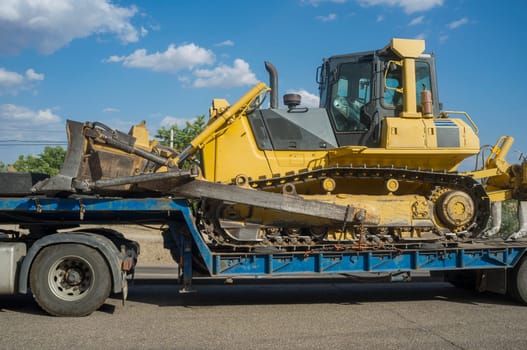 Heavy-duty truck carrying bulldozer equipped with multishank ripper. Heavy duty transports