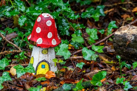 Artificial childhood display of a fly agaric red and white wooden house mushroom in an enchanted fairy toadstool woodland during the autumn fall season of November, stock image photo