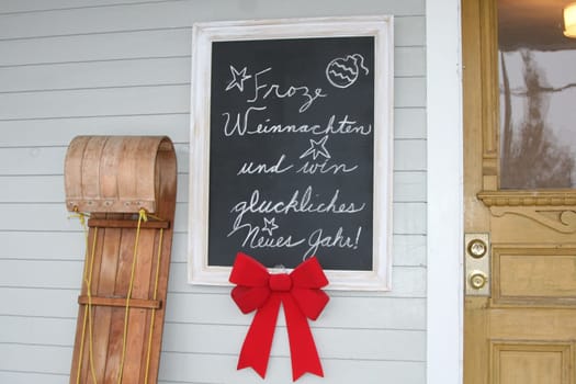 House with blackboard with message Translation: Merry Christmas and a Happy New Year