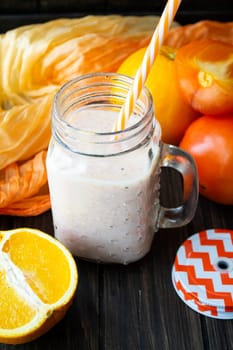 Healthy persimmon and orange smoothie in glass jars, vertical image