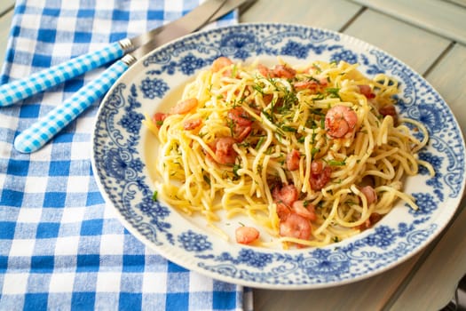 Spaghetti with shrimps and chopped parsley on plate with blue decoration