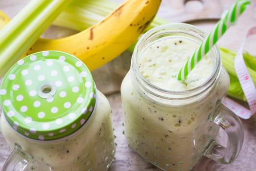 green detox smoothie in glass jars on wooden table close up