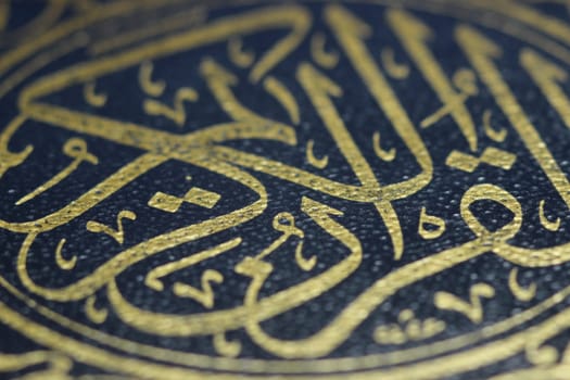 Closeup shot of Islamic Book Quran with golden arabic calligraphy that means Al-Quran, the Holy Quran
