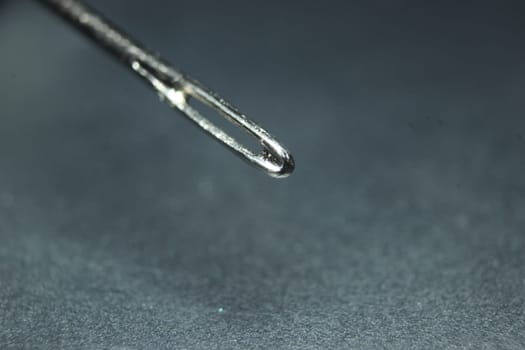 Macro photograph of sewing needle. Small needle with empty eyelet, isolated over the black background.