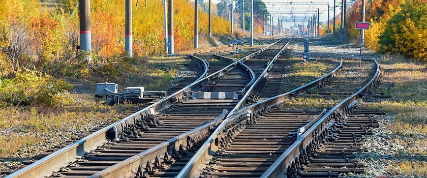 Railway station in a beautiful autumn forest with colorful trees. Many tracks, rails, sleepers, railway background.
