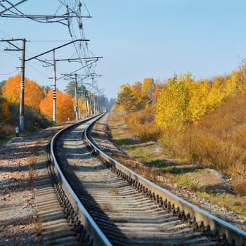 The railway passes through a beautiful autumn forest with colorful trees. The road turns, the railway background.