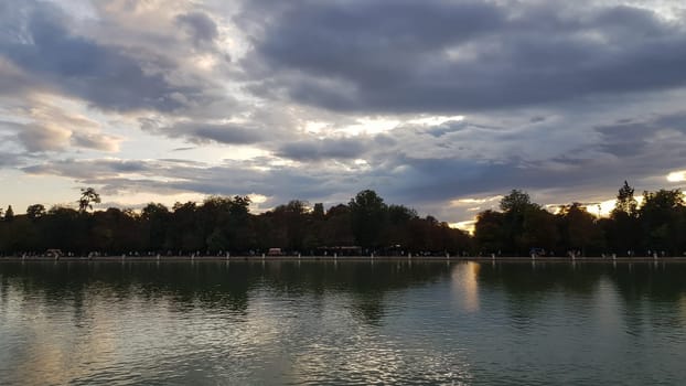 Trees and clouds reflecting in the water during sunset in Buen Retiro Park Madrid