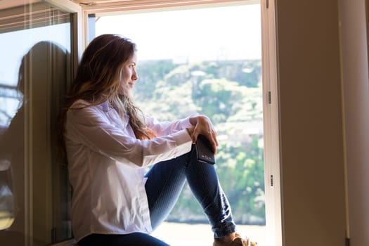 Happy young woman catching some sun at the balcony