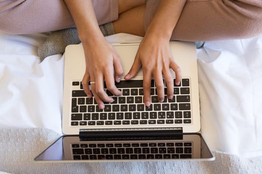 Young woman relaxing with her computer in bed