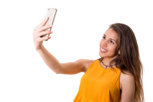 Happy young woman taking self portrait photography through smart phone over white background.
