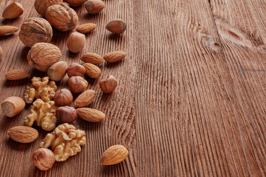 Different kinds nuts. Various varieties of  whole nuts and kernels on brown textured wooden background with copy space. Top view with copy space. Healthy food. Vegetarian food