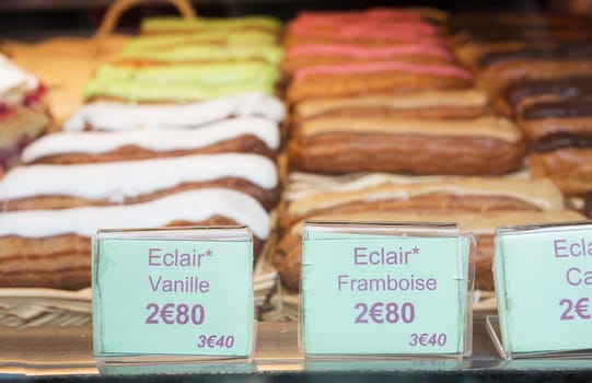 Local patiserie in Paris showing the typical french pastries: Eclairs of vanilla and raspberry