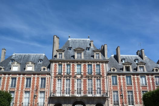 PARIS, FRANCE - August 14, 2016: People relaxing on green lawns of the famous Place des Vosges - the oldest planned square in Paris located in Marais district