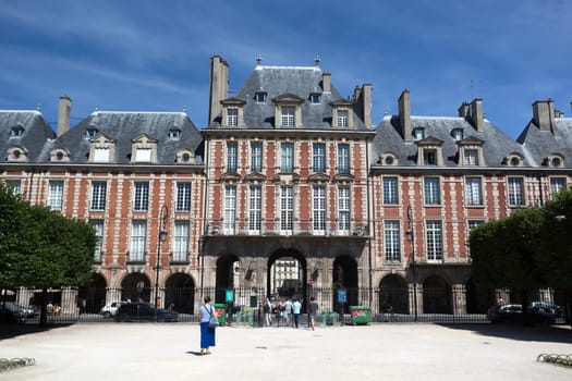 PARIS, FRANCE - August 14, 2016: People relaxing on green lawns of the famous Place des Vosges - the oldest planned square in Paris located in Marais district