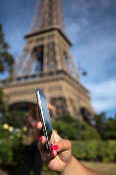 Woman consulting her smartphone with Eiffel Tower on background