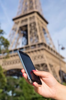 Woman consulting her smartphone with Eiffel Tower on background