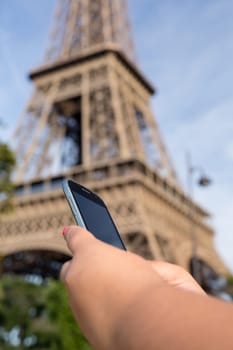 Woman consulting her smartphone with Eiffel Tower on background