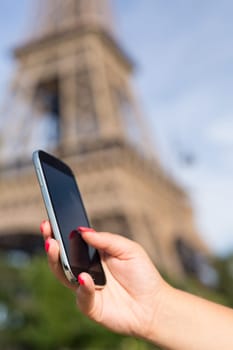 Woman consulting her smartphone with Eiffel Tower on background
